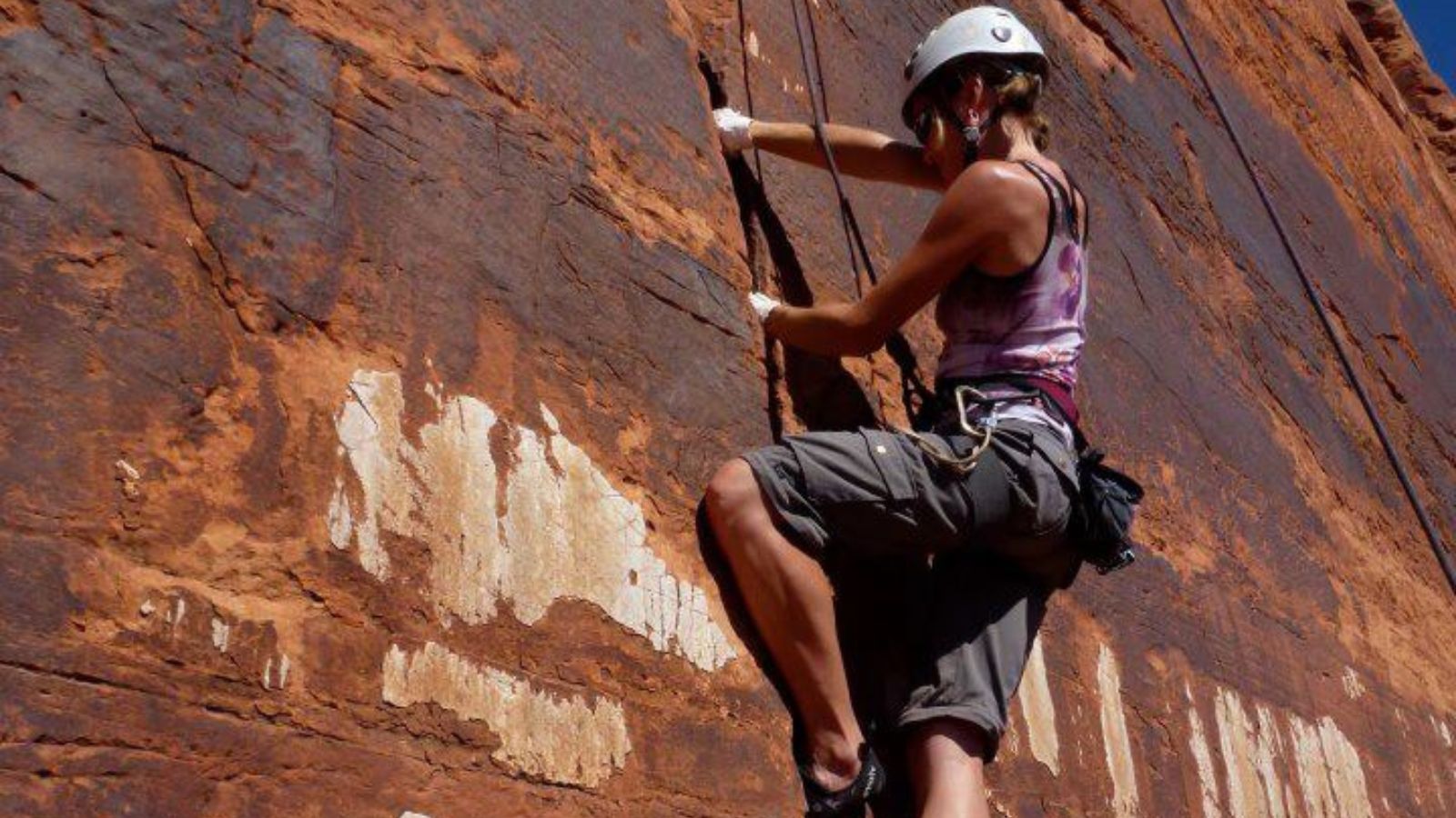 climbing in moab a woman climbs a cracked rock formation in Moab