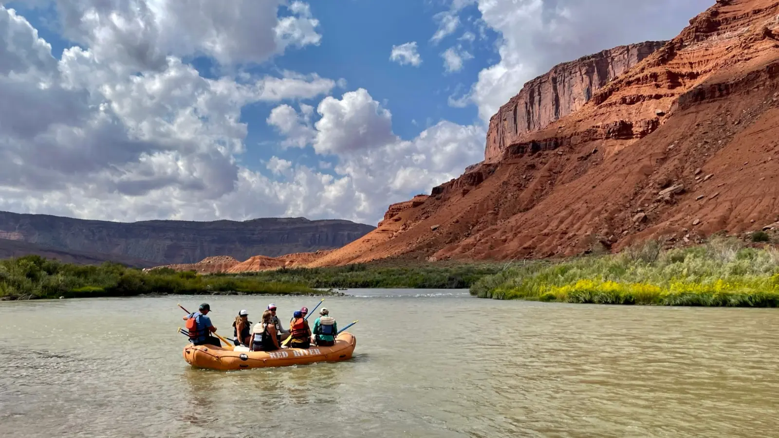 moab tours An orange boat floats down a scenic river canyon